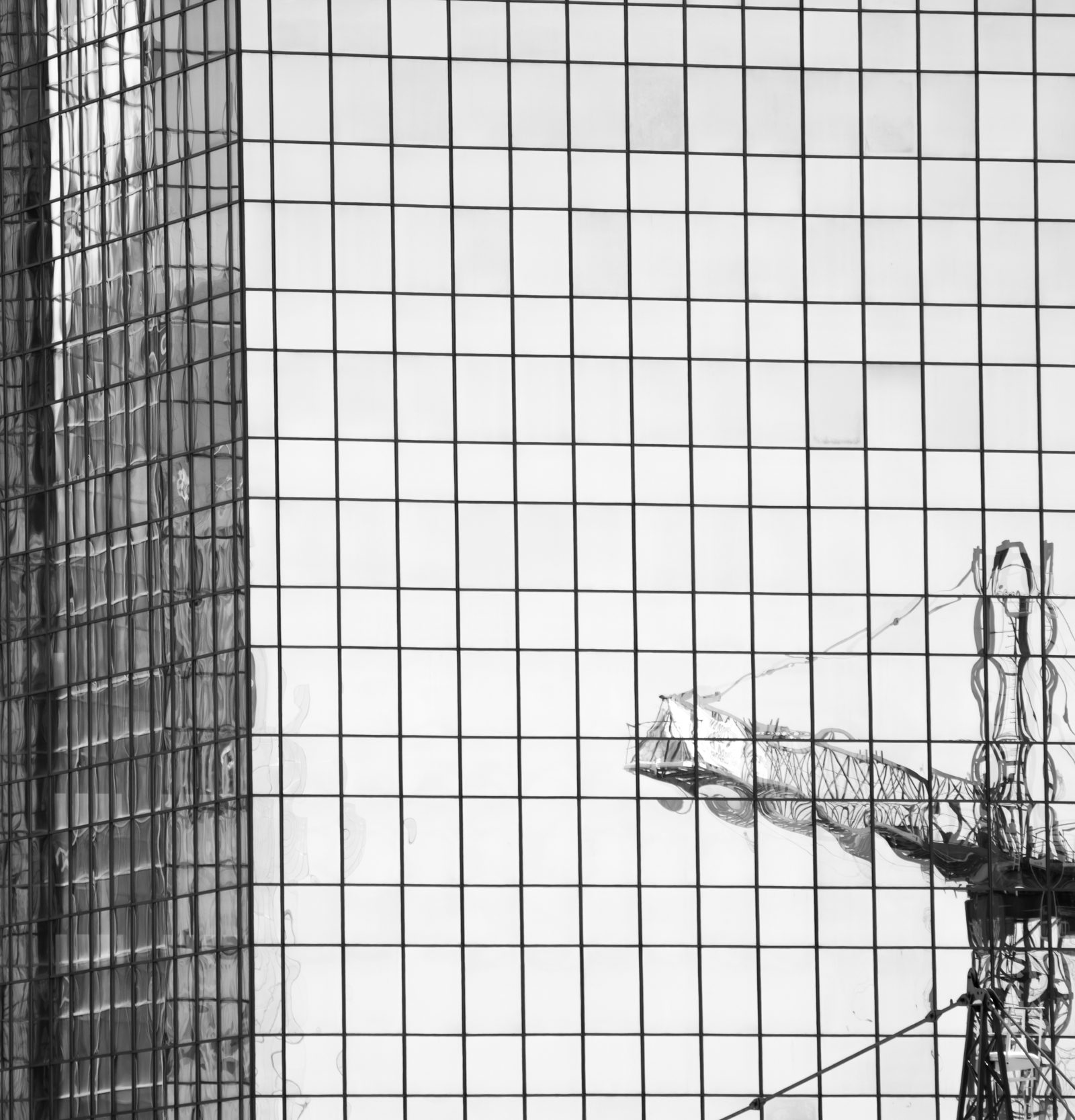 Glass building with reflection of a crane